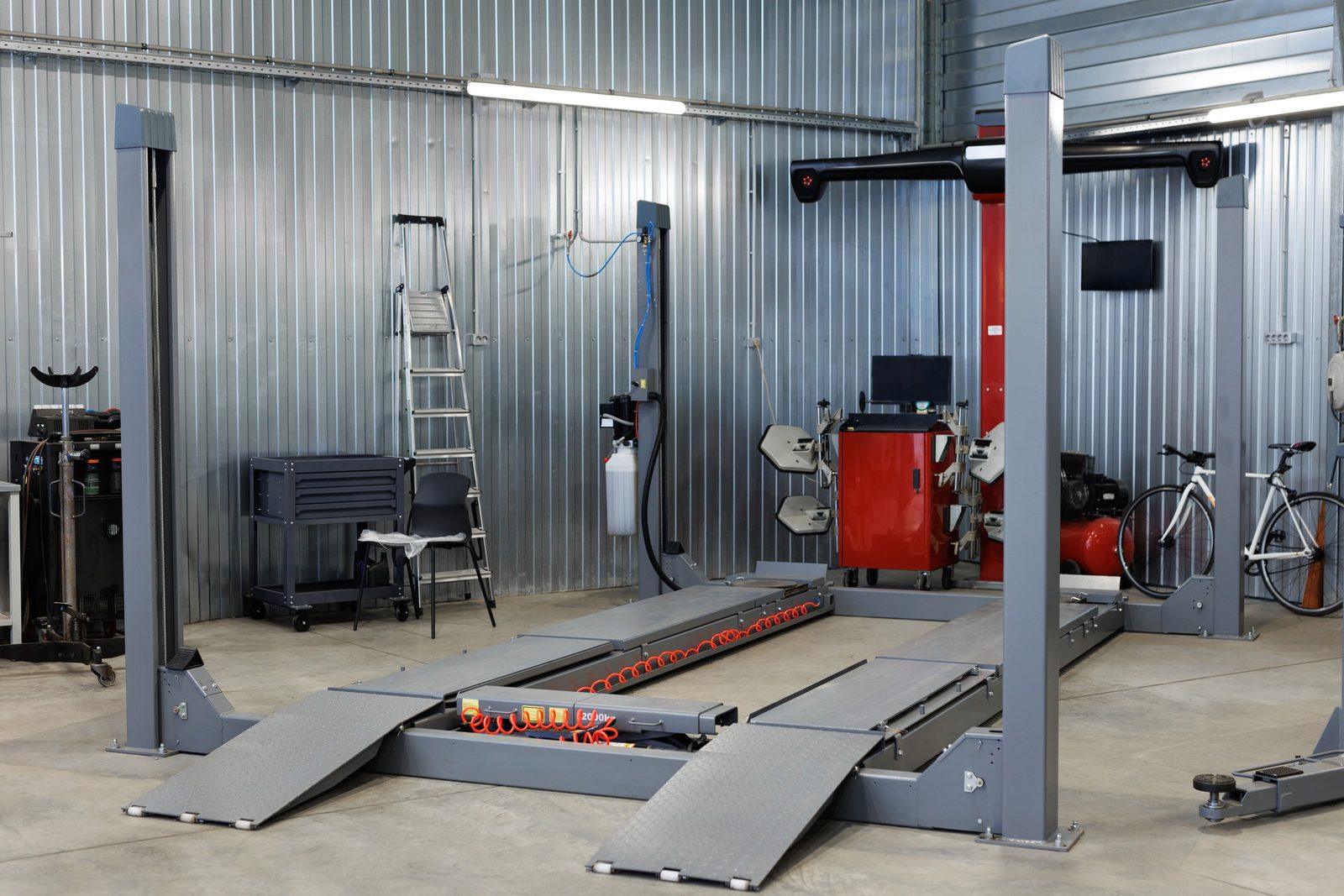 Glossy light-gray epoxy floor reflecting blue car lifts in a clean automotive shop